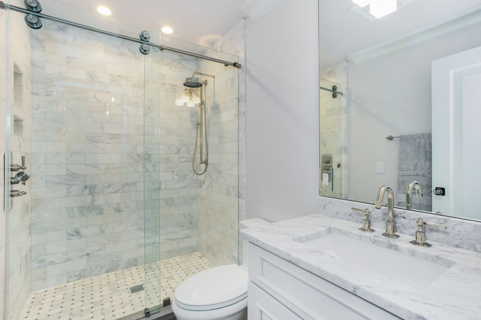 Klassisk inredning av ett mellanstort grå grått badrum med dusch, med luckor med upphöjd panel, vita skåp, en öppen dusch, en toalettstol med separat cisternkåpa, grå kakel, grå väggar, ett undermonterad handfat, marmorbänkskiva, svart golv och dusch med skjutdörr