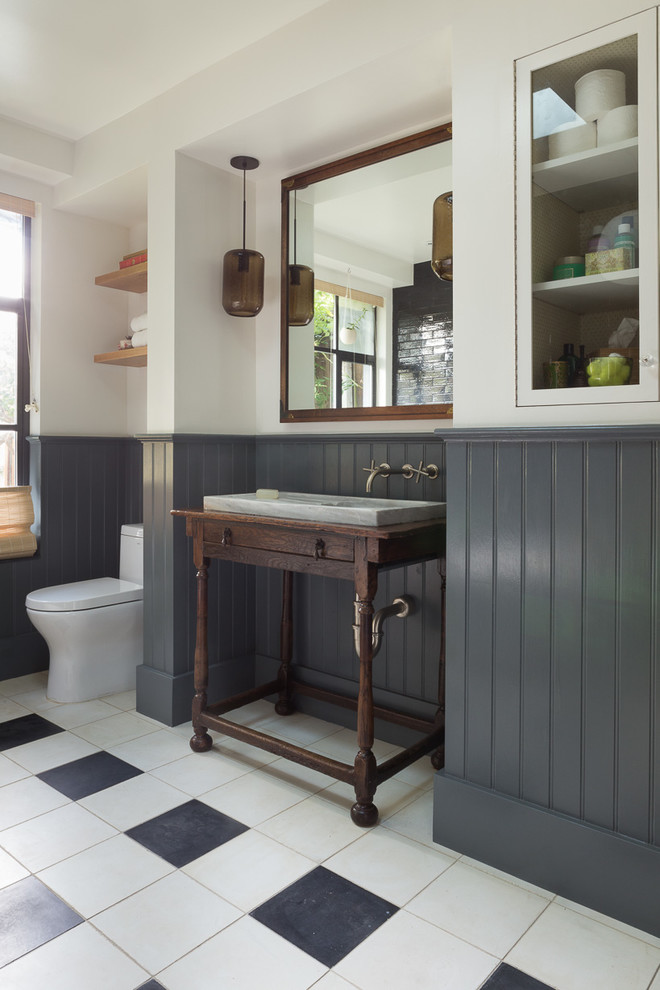 Modelo de cuarto de baño principal y azulejo de dos tonos bohemio de tamaño medio con lavabo tipo consola, puertas de armario de madera en tonos medios, paredes blancas, bañera exenta, ducha empotrada, baldosas y/o azulejos negros, baldosas y/o azulejos de cemento, suelo de baldosas de porcelana, encimera de madera y encimeras marrones