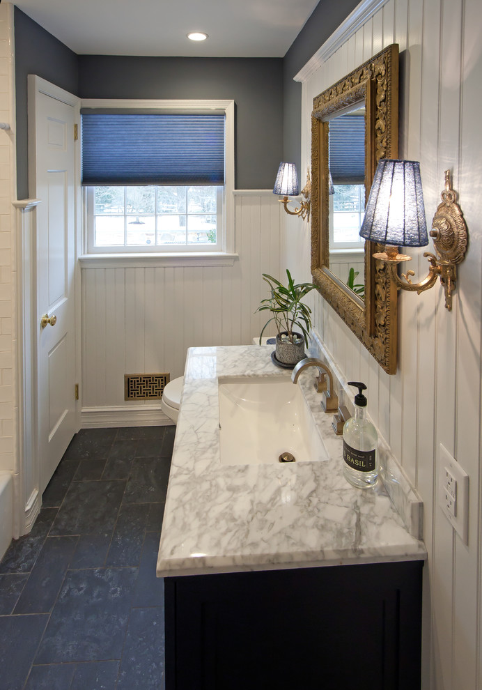 Aménagement d'une salle de bain classique de taille moyenne avec un placard à porte shaker, des portes de placard bleues, une baignoire en alcôve, un combiné douche/baignoire, WC à poser, un carrelage blanc, un lavabo encastré, un sol gris, une cabine de douche avec un rideau, un plan de toilette blanc, un mur gris, un sol en ardoise et un plan de toilette en marbre.