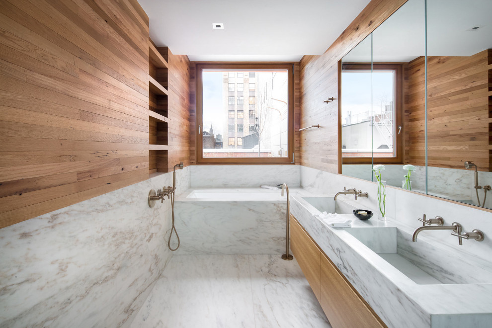 Пример оригинального дизайна: большая главная ванная комната в стиле модернизм с плоскими фасадами, светлыми деревянными фасадами, полновстраиваемой ванной, душем в нише, серой плиткой, мраморной плиткой, коричневыми стенами, мраморным полом, монолитной раковиной, мраморной столешницей, белым полом, душем с распашными дверями и серой столешницей