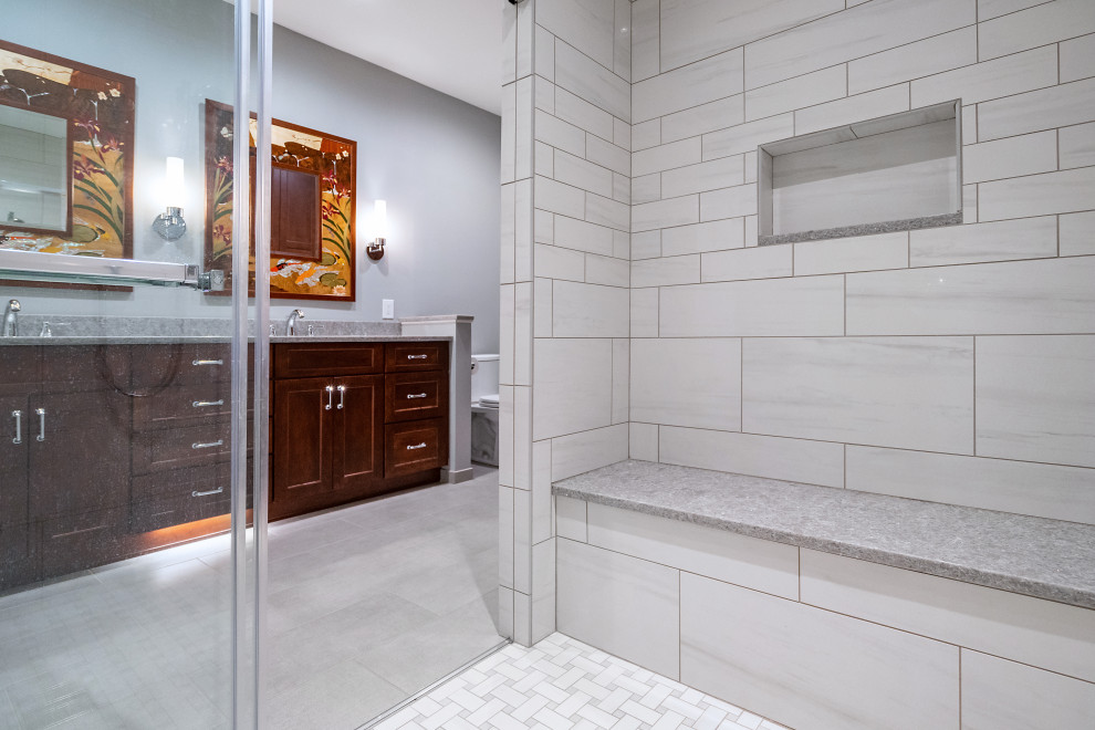 Inspiration for a medium sized classic ensuite bathroom in Philadelphia with shaker cabinets, medium wood cabinets, an alcove shower, a two-piece toilet, white tiles, porcelain tiles, grey walls, porcelain flooring, a submerged sink, engineered stone worktops, grey floors, a sliding door and grey worktops.
