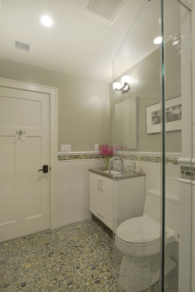 На фото: ванная комната среднего размера в стиле неоклассика (современная классика) с фасадами островного типа, белыми фасадами, душем в нише, унитазом-моноблоком, белой плиткой, керамогранитной плиткой, серыми стенами, полом из галечной плитки, душевой кабиной, врезной раковиной, столешницей из искусственного камня, зеленым полом и душем с распашными дверями с