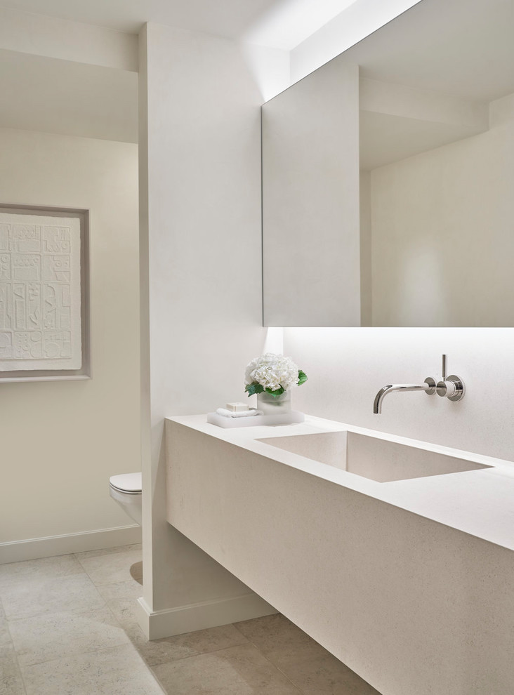 Immagine di una stanza da bagno minimal con pareti bianche, lavabo integrato, pavimento grigio e top bianco