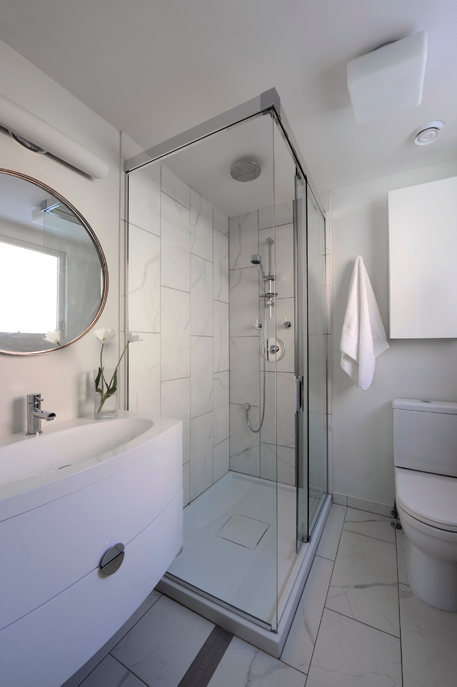 Inspiration för ett litet minimalistiskt en-suite badrum, med ett integrerad handfat, släta luckor, vita skåp, marmorbänkskiva, en hörndusch, en toalettstol med hel cisternkåpa, vit kakel, stenkakel, vita väggar och klinkergolv i porslin