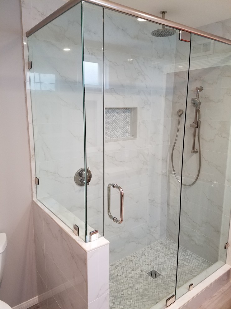 Example of a mid-sized minimalist master white tile and marble tile porcelain tile and brown floor corner shower design in Orange County with recessed-panel cabinets, white cabinets, a two-piece toilet, gray walls, an undermount sink, quartz countertops and a hinged shower door