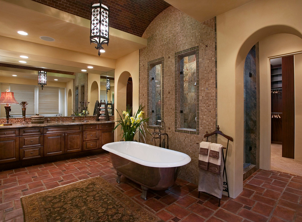 Cette image montre une salle de bain méditerranéenne avec une baignoire indépendante, mosaïque et tomettes au sol.