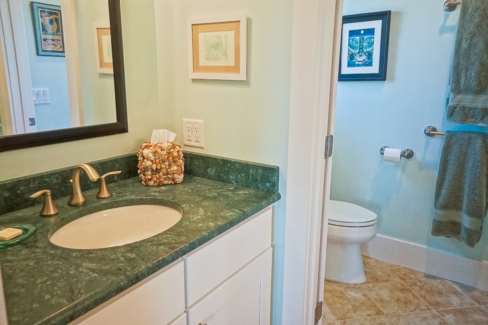 Foto på ett mellanstort maritimt grön badrum med dusch, med skåp i shakerstil, vita skåp, beige kakel, keramikplattor, gröna väggar, klinkergolv i keramik, ett undermonterad handfat och laminatbänkskiva