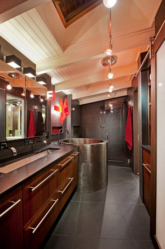 Bild på ett funkis badrum, med ett avlångt handfat, släta luckor, skåp i mörkt trä, ett japanskt badkar, en dusch i en alkov och grå kakel
