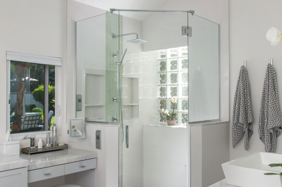 Cette image montre une grande salle de bain principale minimaliste avec un placard à porte shaker, des portes de placard grises, une douche d'angle, WC à poser, un carrelage blanc, des carreaux de porcelaine, un mur blanc, un sol en carrelage de porcelaine, une vasque, un plan de toilette en marbre, un sol gris, une cabine de douche à porte battante et une baignoire indépendante.