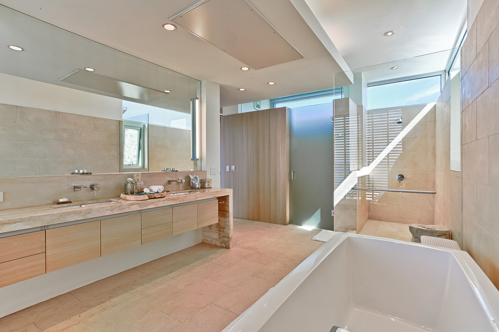 Идея дизайна: большая главная ванная комната в современном стиле с плоскими фасадами, светлыми деревянными фасадами, отдельно стоящей ванной, угловым душем, бежевой плиткой, каменной плиткой, бежевыми стенами, накладной раковиной и мраморной столешницей