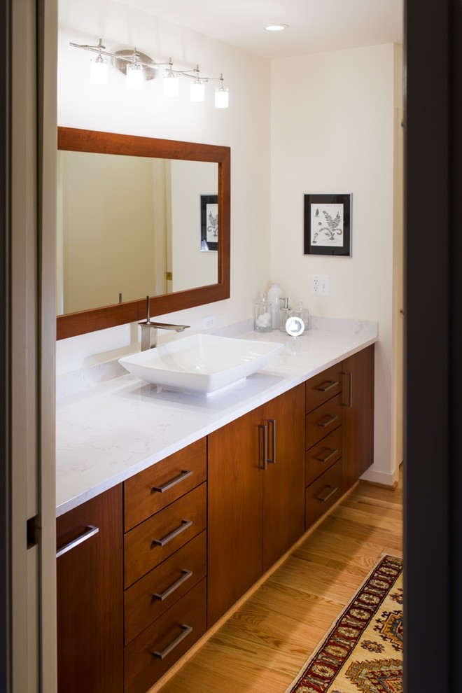 Idée de décoration pour une grande salle de bain principale minimaliste en bois brun avec une vasque, un placard à porte plane, un mur blanc, parquet clair et un plan de toilette en marbre.