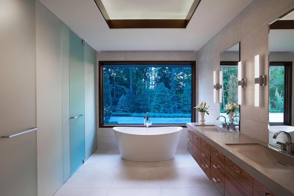 Immagine di una stanza da bagno padronale design con ante lisce, ante in legno bruno, vasca freestanding, lavabo integrato, pavimento grigio e top grigio