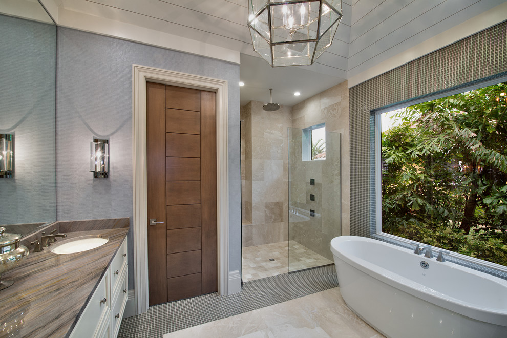 Idée de décoration pour une grande salle de bain principale design avec des portes de placard blanches, une baignoire indépendante, une douche à l'italienne, un carrelage beige et un mur bleu.