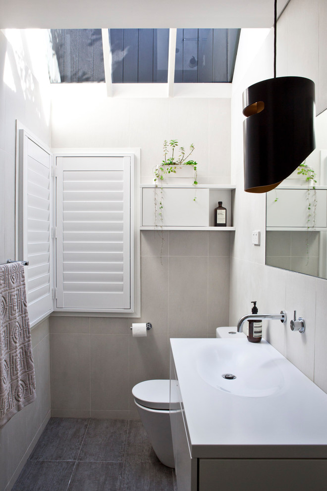 Idéer för mellanstora funkis badrum med dusch, med släta luckor, vita skåp, en toalettstol med hel cisternkåpa, beige kakel, keramikplattor, beige väggar, klinkergolv i keramik, ett integrerad handfat, bänkskiva i akrylsten och brunt golv