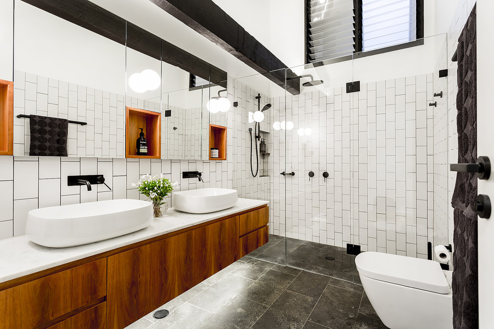 シドニーにある広いインダストリアルスタイルのおしゃれな浴室 (一体型トイレ	、黒いタイル、白いタイル、セラミックタイル、白い壁、セラミックタイルの床、大理石の洗面台、グレーの床、フラットパネル扉のキャビネット、濃色木目調キャビネット、開き戸のシャワー) の写真