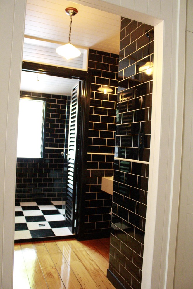 Réalisation d'une salle de bain tradition avec un lavabo suspendu, une douche ouverte, WC séparés, un carrelage noir, un carrelage métro, un mur noir et parquet clair.