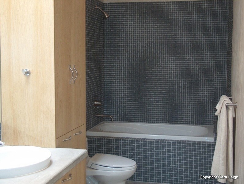 Idées déco pour une petite salle de bain contemporaine en bois clair avec une baignoire posée, un combiné douche/baignoire, WC à poser, un carrelage gris, des plaques de verre, un mur gris, sol en béton ciré et une vasque.