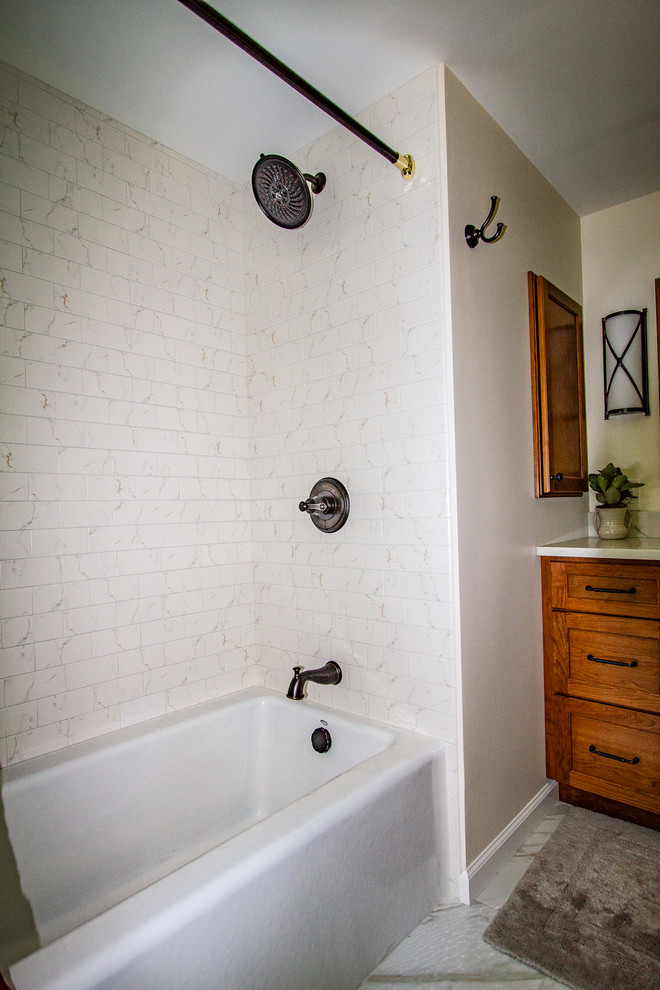 This is an example of a medium sized classic ensuite bathroom in Philadelphia with recessed-panel cabinets, medium wood cabinets, a built-in bath, a shower/bath combination, a two-piece toilet, white tiles, metro tiles, yellow walls, marble flooring, a submerged sink, quartz worktops, white floors, a shower curtain and white worktops.
