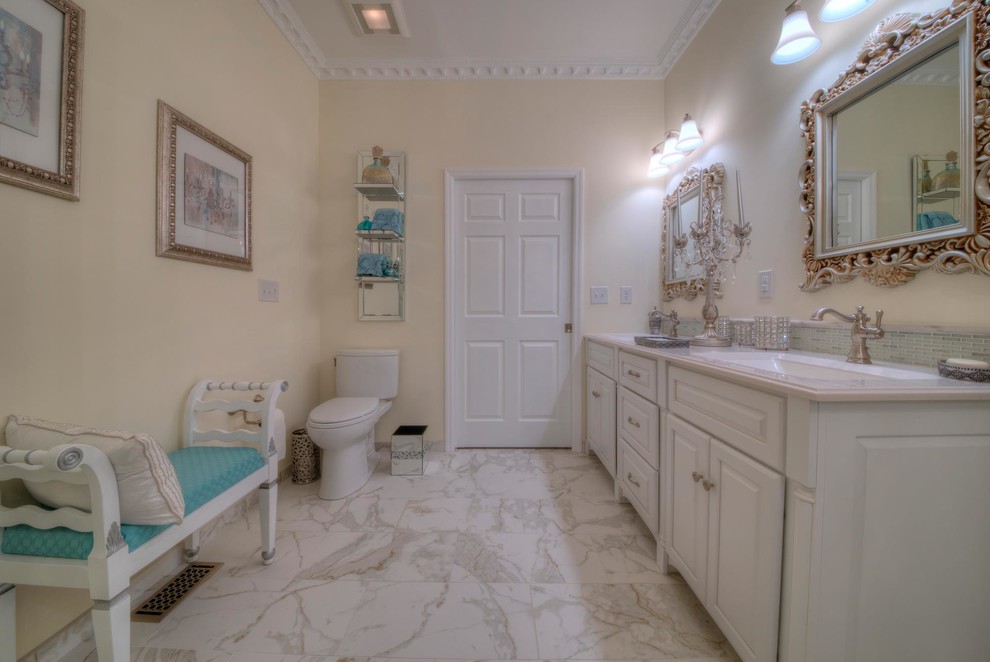 Идея дизайна: большая главная ванная комната в классическом стиле с фасадами с выступающей филенкой, белыми фасадами, отдельно стоящей ванной, душем без бортиков, раздельным унитазом, желтыми стенами, полом из керамогранита, монолитной раковиной, столешницей из оникса, разноцветным полом и душем с распашными дверями