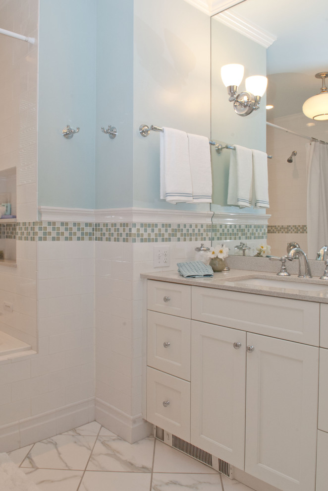 Cette photo montre une salle de bain chic de taille moyenne avec un placard à porte shaker, des portes de placard blanches, une baignoire posée, un combiné douche/baignoire, WC séparés, un carrelage blanc, des carreaux de céramique, un mur bleu, un sol en carrelage de porcelaine, un lavabo encastré et un plan de toilette en quartz modifié.