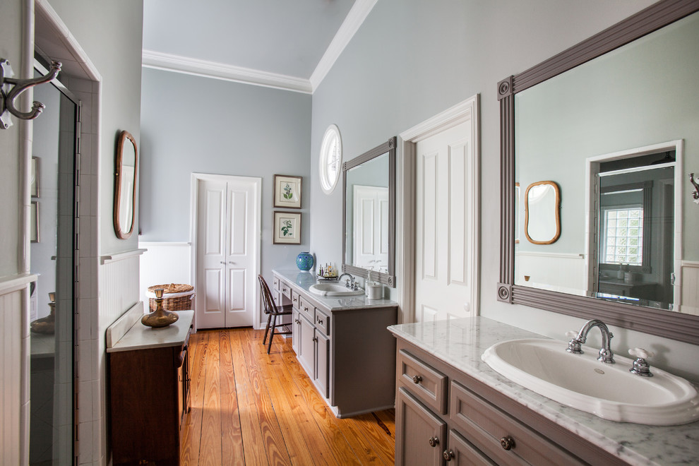 Bathroom - large traditional master white tile and porcelain tile medium tone wood floor bathroom idea in Houston with a drop-in sink, recessed-panel cabinets, gray cabinets, marble countertops and gray walls