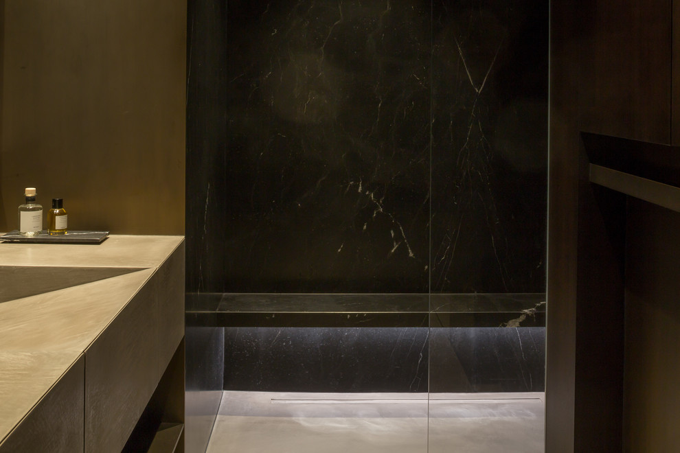 Immagine di una stanza da bagno con doccia design di medie dimensioni con ante in legno bruno, doccia aperta, piastrelle nere, lastra di pietra, pareti marroni, pavimento in cemento e top in cemento