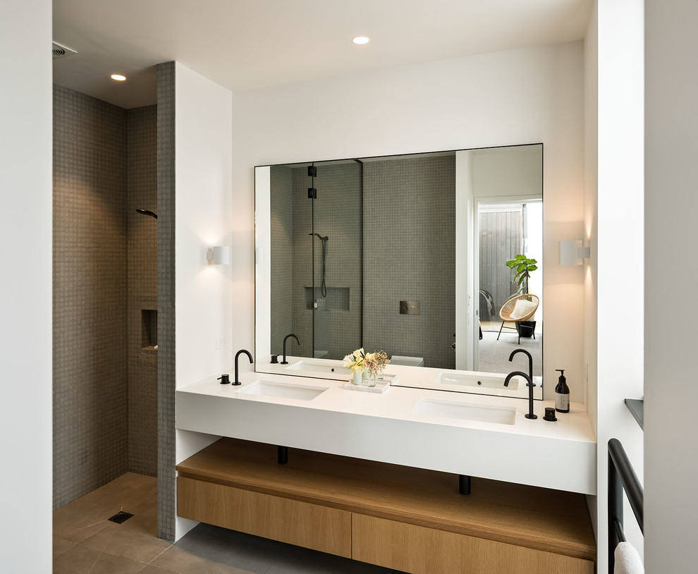 Modernes Badezimmer mit flächenbündigen Schrankfronten, hellbraunen Holzschränken, Duschnische, grauen Fliesen, Mosaikfliesen, weißer Wandfarbe, Unterbauwaschbecken, grauem Boden, offener Dusche und weißer Waschtischplatte in Sydney
