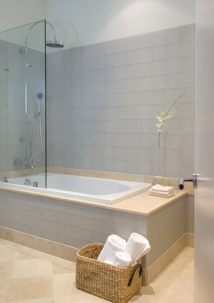 Exemple d'une salle de bain moderne avec un combiné douche/baignoire, un carrelage gris et une baignoire posée.