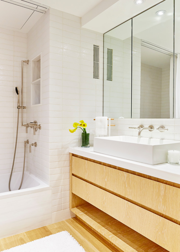Idéer för ett mellanstort modernt badrum, med släta luckor, skåp i slitet trä, ett badkar i en alkov, en toalettstol med hel cisternkåpa, vit kakel, keramikplattor, vita väggar, ljust trägolv, ett undermonterad handfat, marmorbänkskiva och en dusch/badkar-kombination