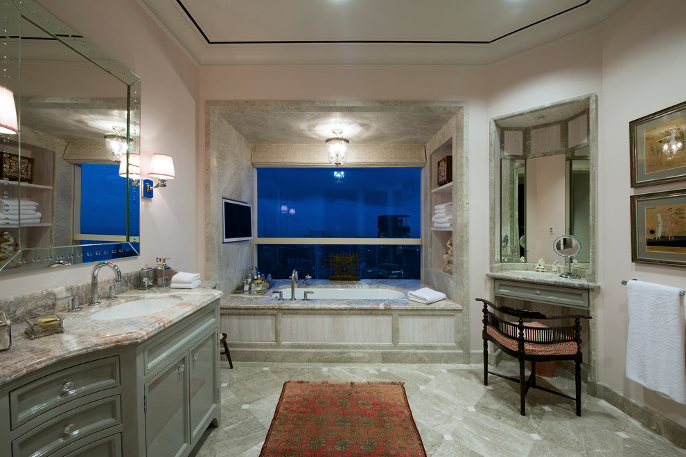 На фото: большая главная ванная комната в стиле неоклассика (современная классика) с врезной раковиной, фасадами с декоративным кантом, серыми фасадами, мраморной столешницей, полновстраиваемой ванной, белыми стенами и мраморным полом