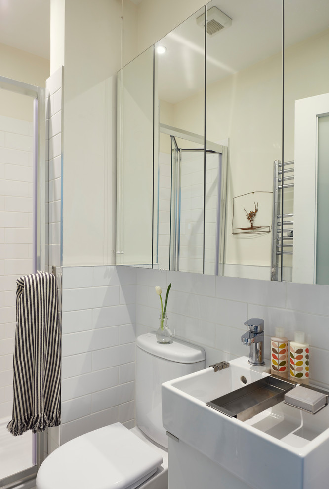 Inredning av ett modernt litet badrum med dusch, med luckor med glaspanel, vita skåp, en öppen dusch, en toalettstol med hel cisternkåpa, vita väggar, vinylgolv, ett väggmonterat handfat, vitt golv och dusch med gångjärnsdörr