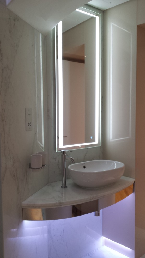 Medium sized contemporary ensuite bathroom in London with a freestanding bath, a wall mounted toilet, black and white tiles, stone tiles, multi-coloured walls, marble flooring, a vessel sink, marble worktops and an alcove shower.