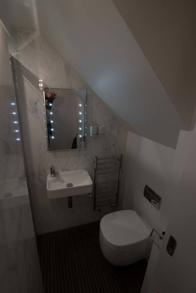Cette photo montre une petite douche en alcôve principale tendance avec WC suspendus, un carrelage noir et blanc, des dalles de pierre, parquet foncé, un lavabo suspendu et un mur multicolore.