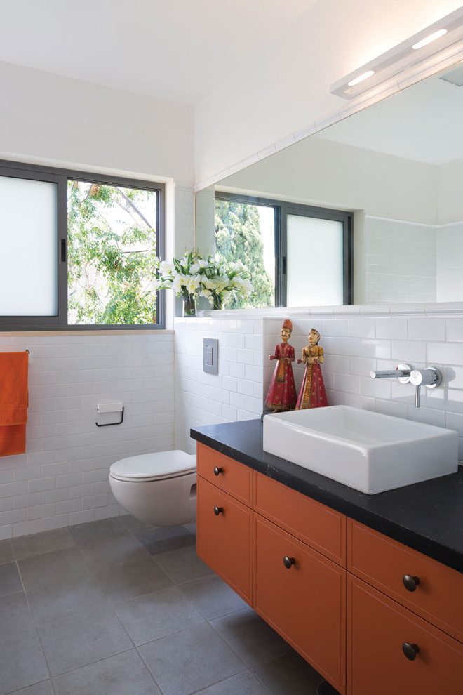 Inredning av ett modernt badrum, med ett fristående handfat, orange skåp och vita väggar