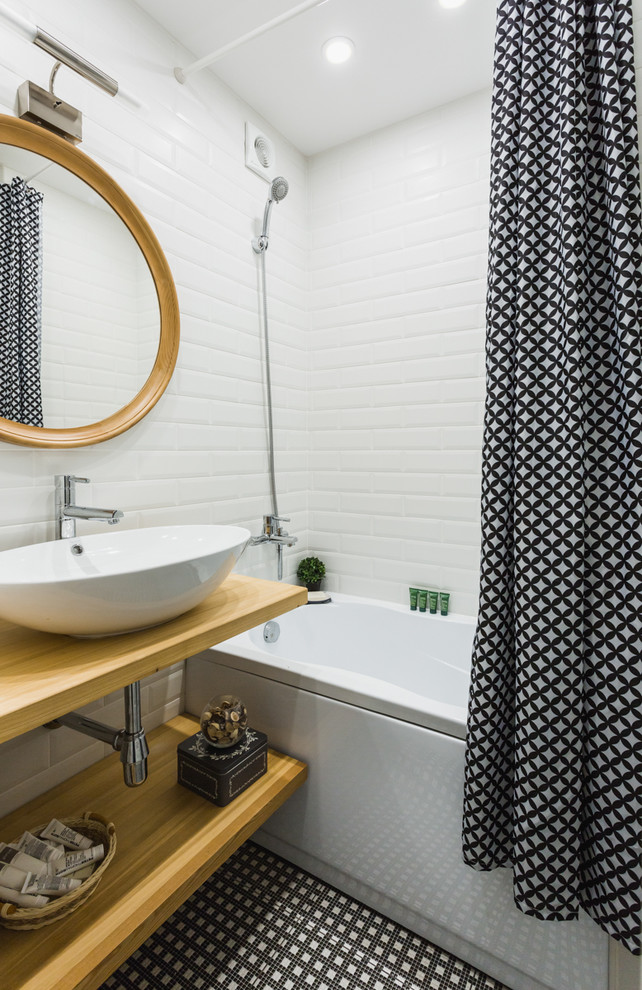 Inredning av ett minimalistiskt beige beige badrum, med en dusch/badkar-kombination, keramikplattor, klinkergolv i keramik, öppna hyllor, ett badkar i en alkov, vit kakel, ett fristående handfat, träbänkskiva, skåp i ljust trä och dusch med duschdraperi