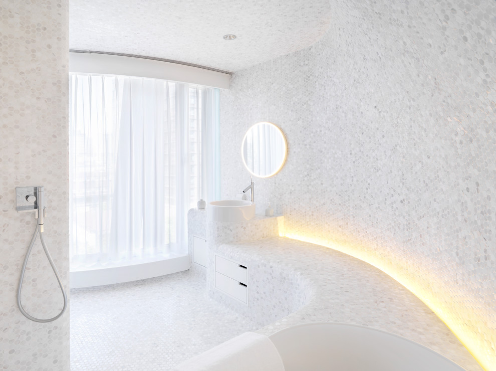 На фото: главная ванная комната среднего размера в современном стиле с белыми фасадами, угловой ванной, душем над ванной, серой плиткой, белыми стенами, мраморным полом и столешницей из плитки