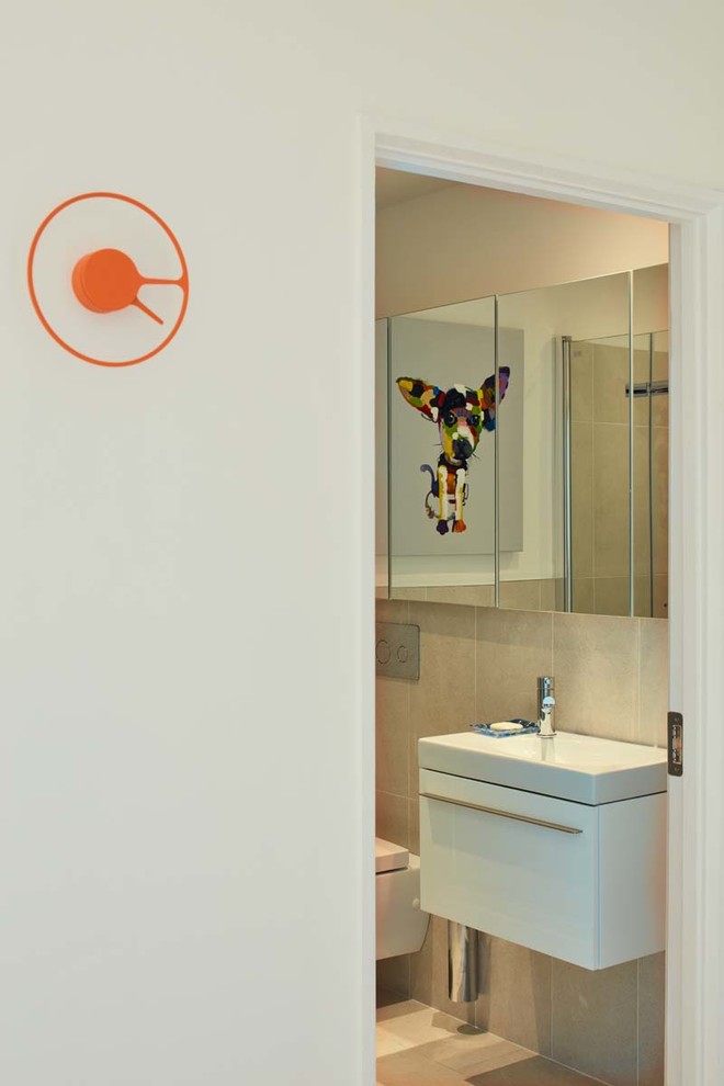 Cette photo montre une salle de bain tendance avec un mur blanc, un sol en bois brun, un placard à porte vitrée, des portes de placard blanches, WC suspendus, un carrelage blanc, des carreaux de céramique et un lavabo intégré.