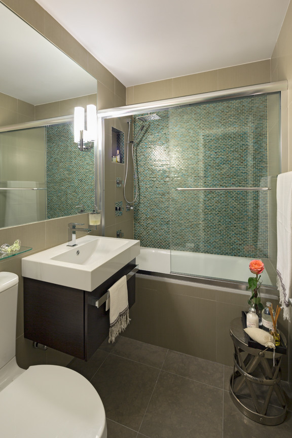 Bild på ett mellanstort funkis en-suite badrum, med släta luckor, skåp i mörkt trä, ett platsbyggt badkar, en dusch/badkar-kombination, en toalettstol med hel cisternkåpa, blå kakel, grön kakel, glaskakel och ett väggmonterat handfat