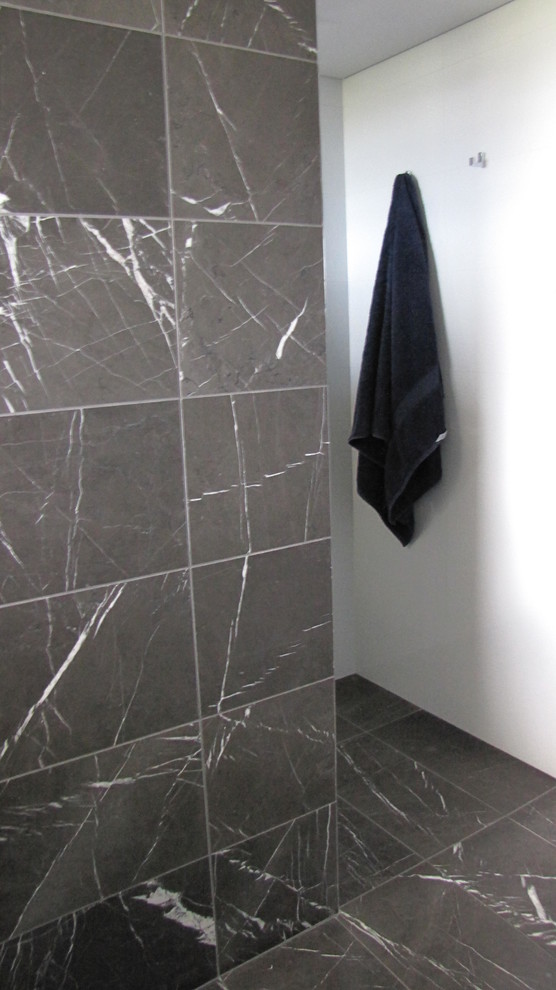 Modern inredning av ett litet en-suite badrum, med möbel-liknande, grå skåp, en hörndusch, en vägghängd toalettstol, grå kakel, marmorkakel, flerfärgade väggar, marmorgolv, ett nedsänkt handfat, granitbänkskiva, flerfärgat golv och dusch med gångjärnsdörr