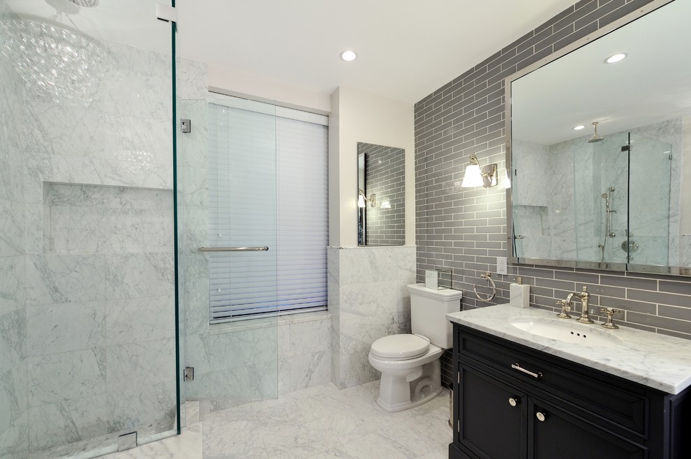 Cette image montre une grande salle de bain design en bois foncé avec un lavabo intégré, un placard avec porte à panneau surélevé, un plan de toilette en bois, une baignoire d'angle, une douche d'angle, WC séparés, un carrelage gris, un mur blanc et un sol en marbre.