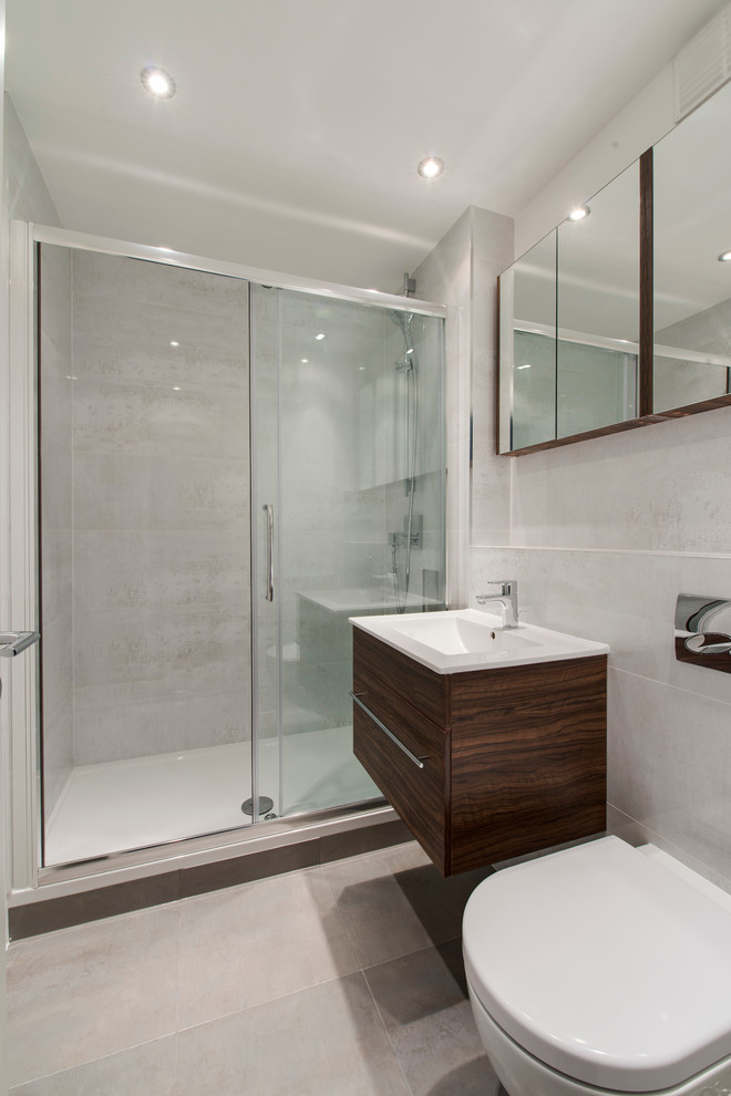 Inspiration för ett funkis badrum med dusch, med ett integrerad handfat, grå kakel, keramikplattor, klinkergolv i porslin, släta luckor, skåp i mörkt trä, en dusch i en alkov och en vägghängd toalettstol