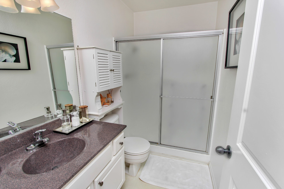 Example of a small beach style linoleum floor alcove shower design in Orange County with an integrated sink, a wall-mount toilet and white walls