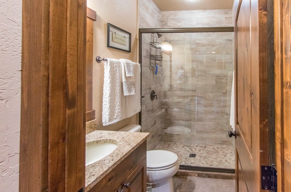 Small arts and crafts 3/4 beige tile, brown tile and stone slab slate floor and brown floor alcove shower photo in Denver with shaker cabinets, medium tone wood cabinets, a two-piece toilet, beige walls, an undermount sink, granite countertops and a hinged shower door