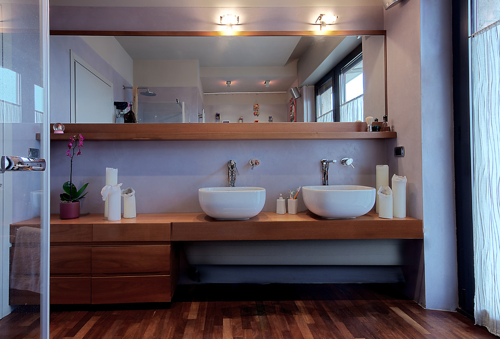 Пример оригинального дизайна: главная ванная комната среднего размера в современном стиле с фасадами с утопленной филенкой, темными деревянными фасадами, накладной ванной, угловым душем, инсталляцией, настольной раковиной, столешницей из дерева, фиолетовыми стенами, темным паркетным полом и коричневой столешницей