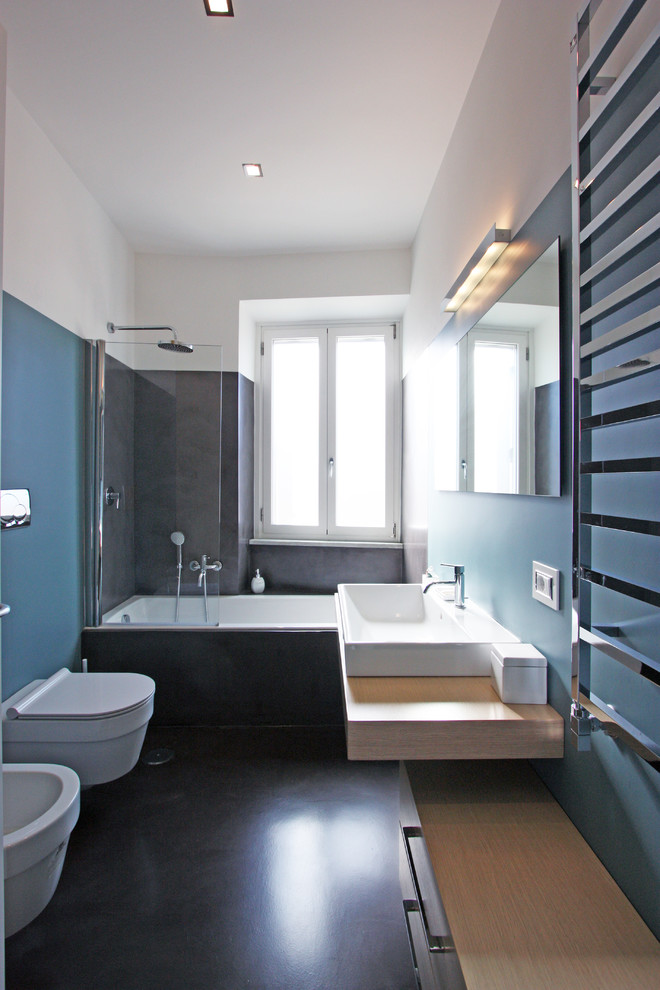 Cette photo montre une salle de bain principale moderne en bois clair de taille moyenne avec un plan vasque, un placard en trompe-l'oeil, une baignoire posée, une douche d'angle, WC suspendus, un mur bleu et sol en béton ciré.