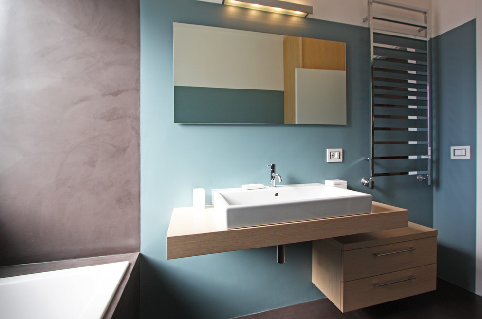 На фото: главная ванная комната среднего размера в стиле модернизм с консольной раковиной, фасадами островного типа, светлыми деревянными фасадами, накладной ванной, угловым душем, инсталляцией, синими стенами и бетонным полом