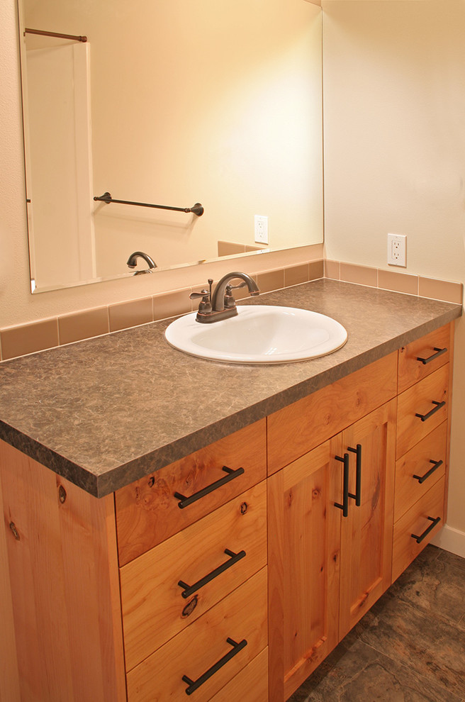 Exemple d'une salle de bain craftsman en bois brun de taille moyenne avec un lavabo posé, un placard à porte shaker, un plan de toilette en stratifié, un carrelage beige, des carreaux de céramique, un mur beige et un sol en linoléum.