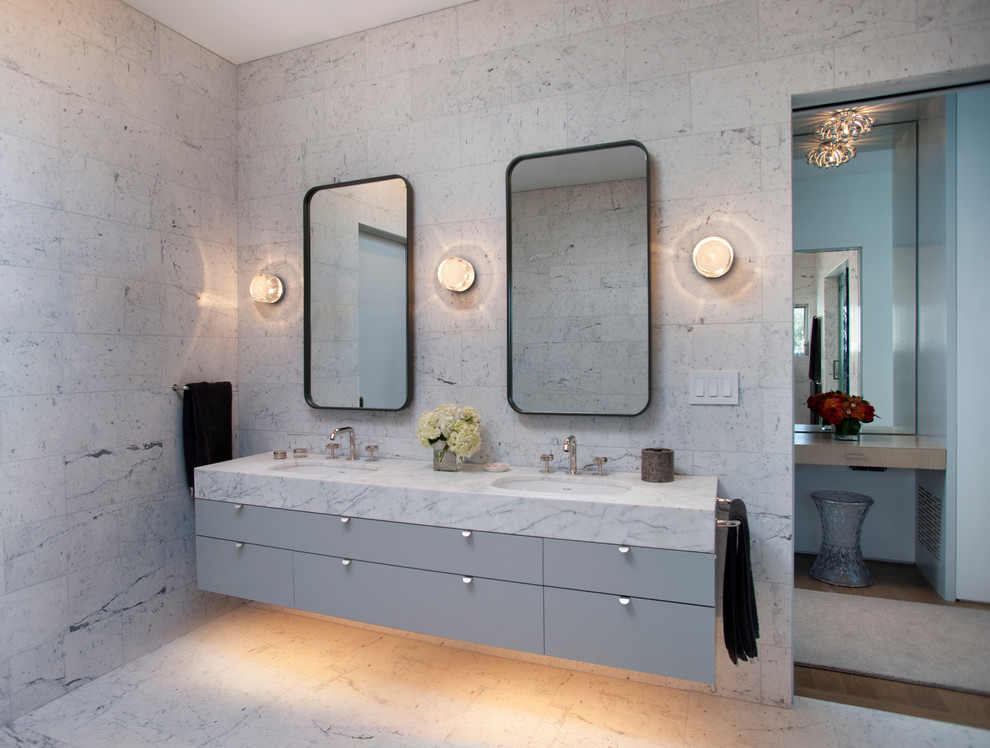 Cette image montre une salle de bain design avec un lavabo encastré, un placard à porte plane, des portes de placard grises et un carrelage blanc.
