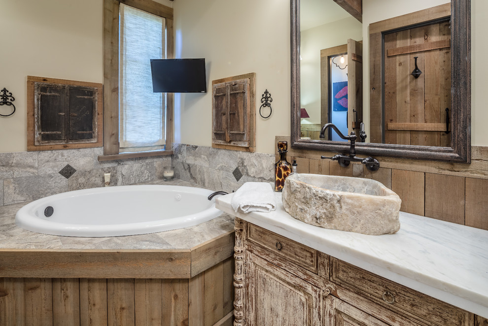 Foto di una stanza da bagno stile rurale con ante con finitura invecchiata, vasca da incasso, piastrelle grigie, pareti beige, lavabo a bacinella, top bianco e ante con bugna sagomata