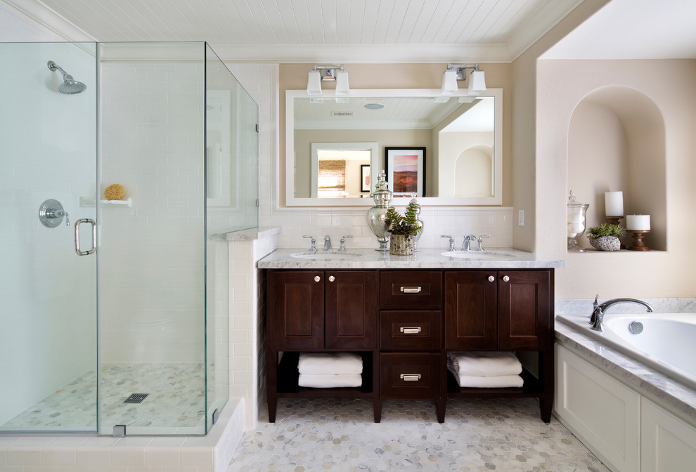 Idée de décoration pour une salle de bain principale tradition en bois foncé avec un lavabo encastré, une baignoire posée, un carrelage blanc, un carrelage métro, un mur beige et un placard à porte shaker.